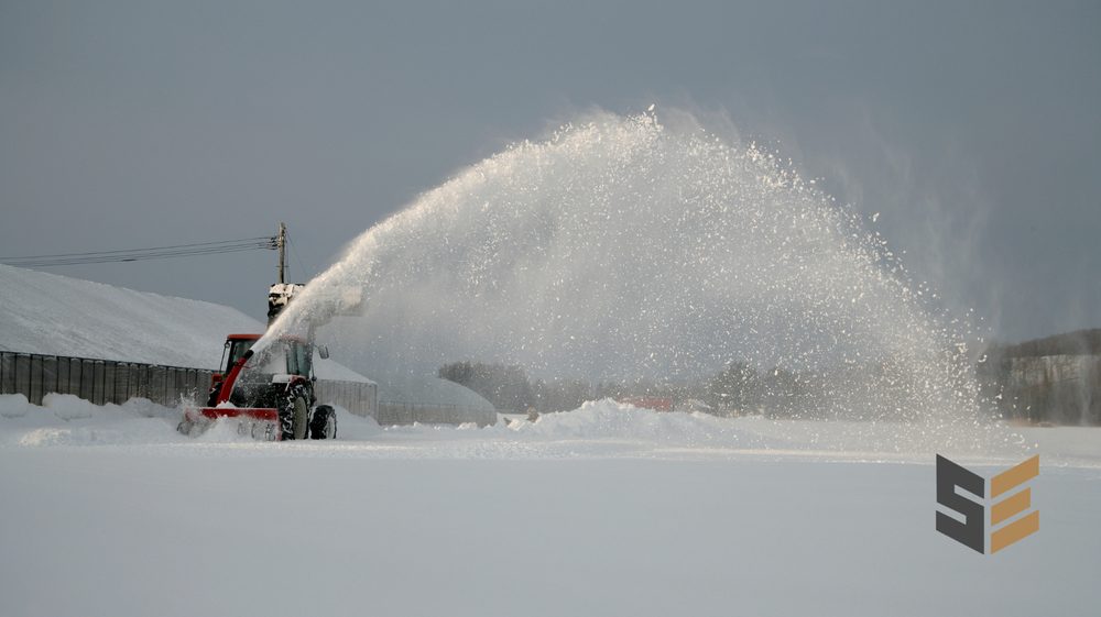 Equipment relocating snow, throwing it clear of the lot